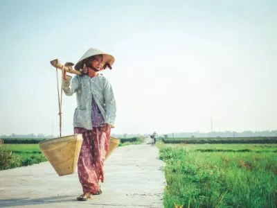 Vietnamese vrouw met manden langs het rijstveld in Vietnam.