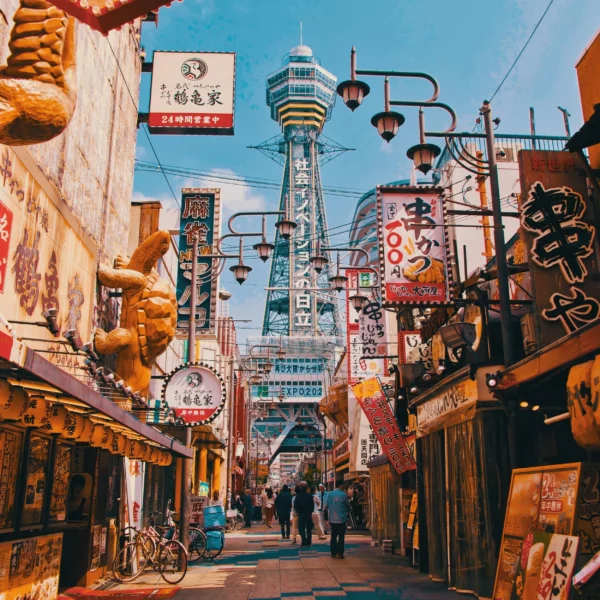 Tsutenkaku-toren torent boven een levendige straat vol kleurrijke uithangborden in Osaka tijdens een rondreis Japan.