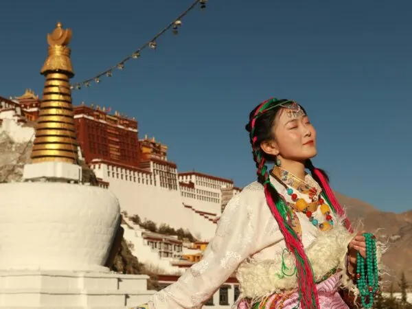 Vrouw voor klooster in Tibet, China.